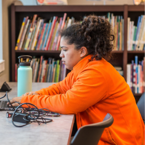 Student in the library working on a laptop
