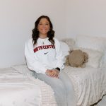 Student sitting on a bed in the dorm room